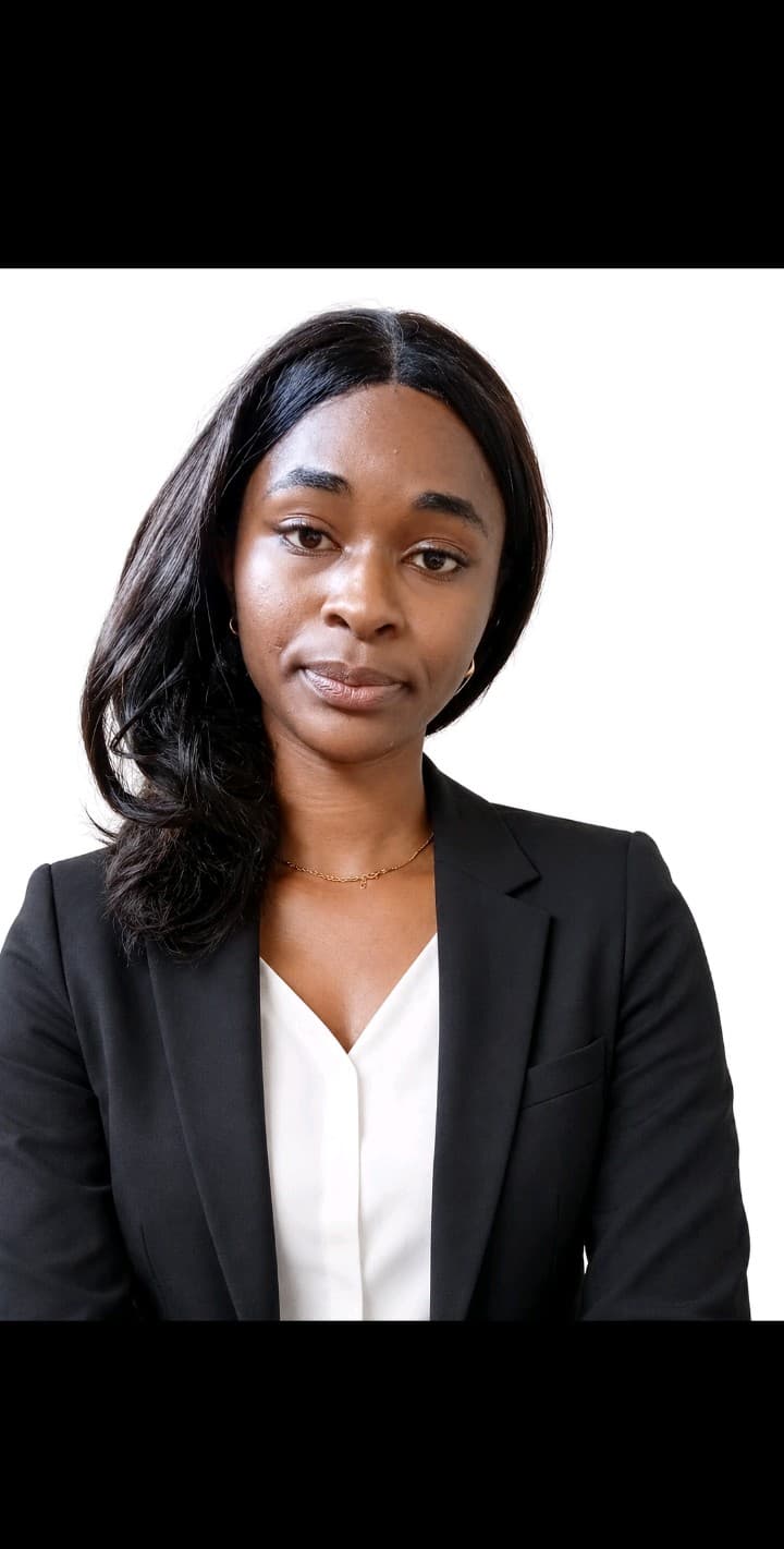 Mulher negra com cabelos longos escuros, vestindo um blazer preto e uma blusa branca.